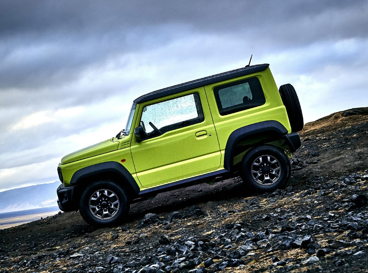 Suzuki Jimny đứng trên sườn đồi đá dưới trời mây