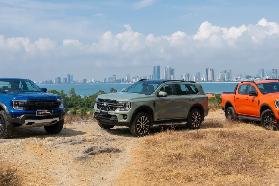 Ranger Raptor màu xanh, Everest màu xanh rêu và Ranger màu cam đỗ trên đồi nhìn ra thành phố ven biển