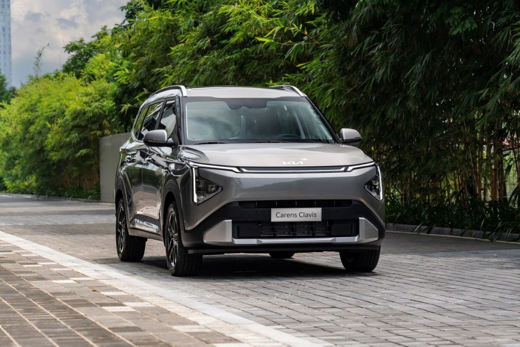Kia Carens Clavis 7 chỗ màu xám chạy trên đường lát gạch