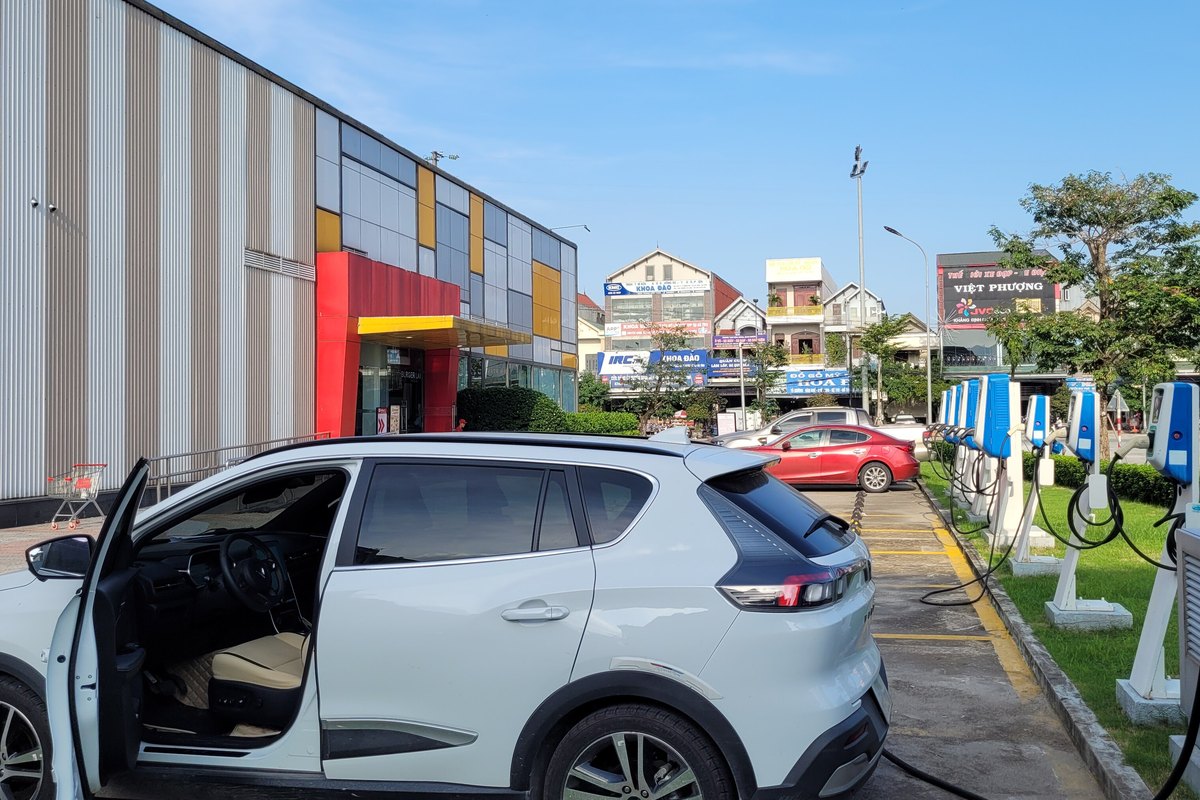 Xe điện đang sạc cạnh dãy trụ sạc tại một bãi đỗ xe